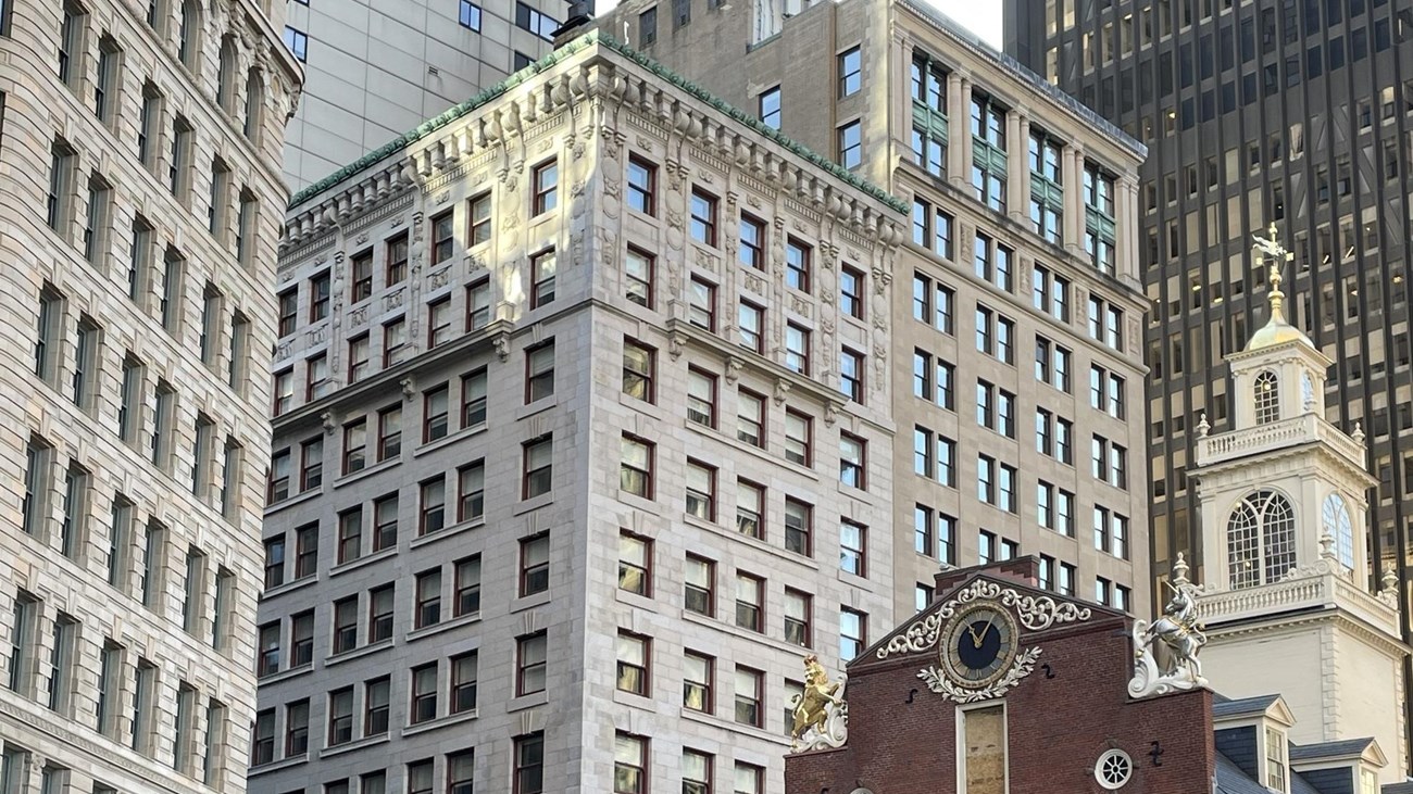 an 11-story building amongst skyskrapers and next to a historic brick building