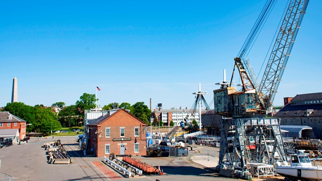 A crane and buildings at a navy yard. 