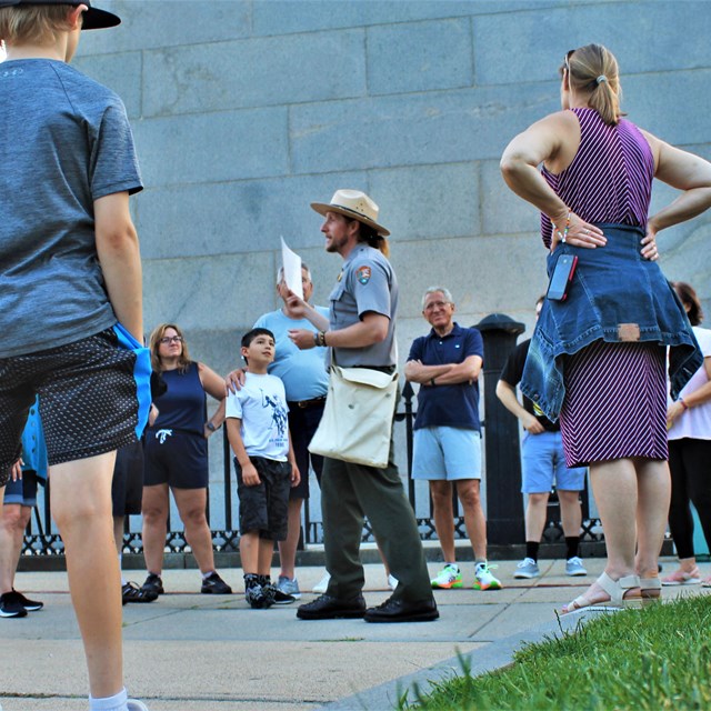 Ranger in front of the Bunker Hill Monument talking to a group of visitors around him.