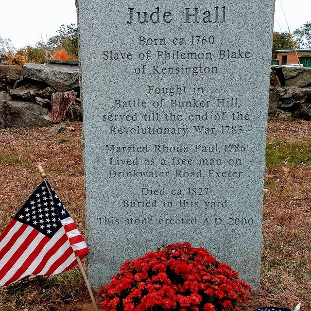 gravestone with flowers and two small American flags