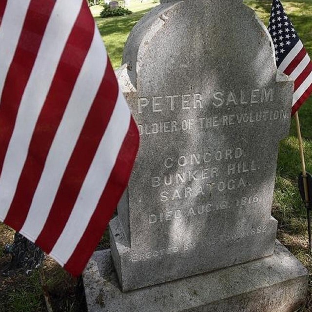 gravestone with two American flags on either side.