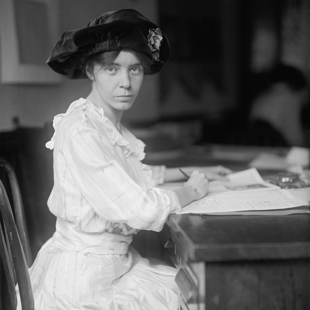 Suffragist Alice Paul sitting at desk