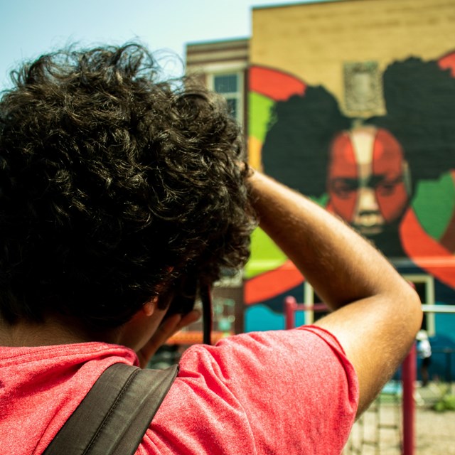 A young person taking a picture of a mural.