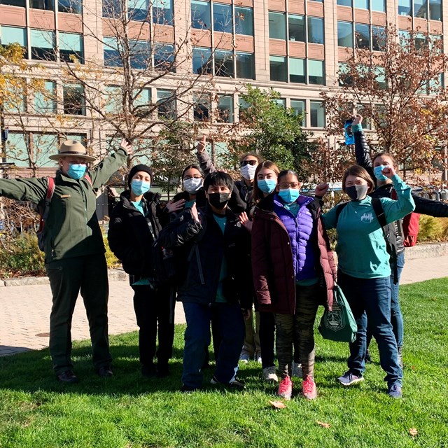 Group of young people with a ranger standing for a group photo outside.