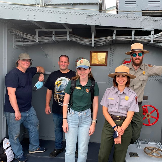 A group of two rangers, two volunteers, and a intern standing on the deck of a ship. 