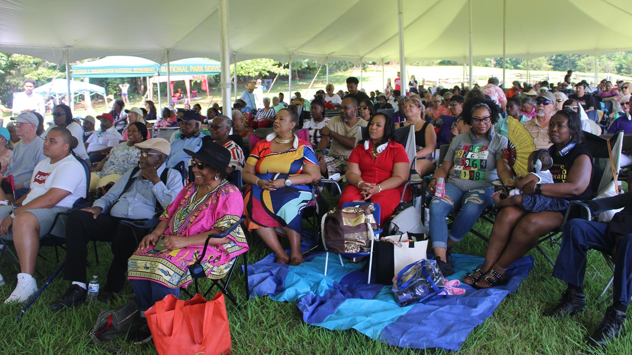 A group of seated concert goers looking on with smiles.