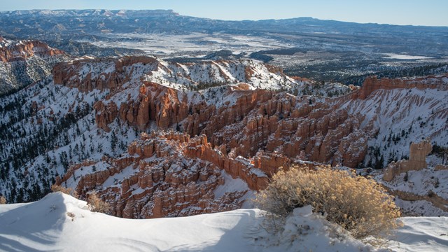 A view from above of a snowy red rock-filled amphitheater.