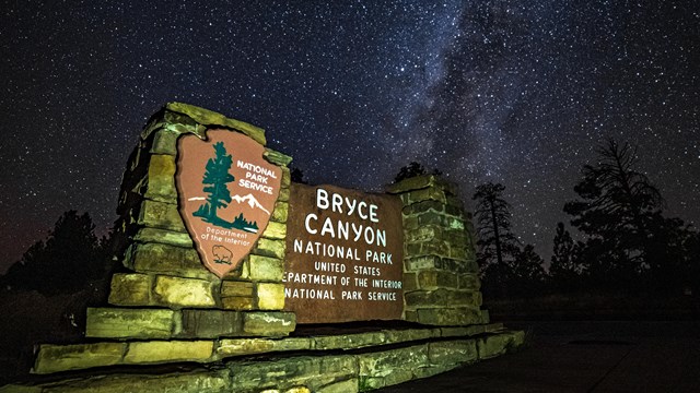 An illuminated Bryce Canyon sign with a dark sky background with lots of stars.