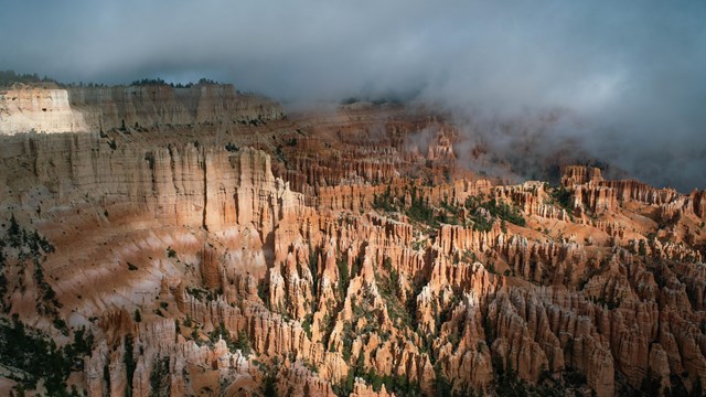 Dark storm clouds threaten above an amphitheater of red rock formations.