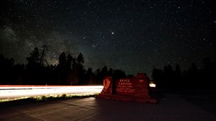Entrance sign for Bryce Canyon National Park beneath the Milky Way