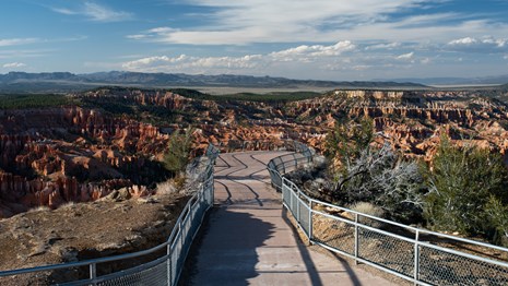 View of empty fenced viewpoint overlooking red rocks and green forest