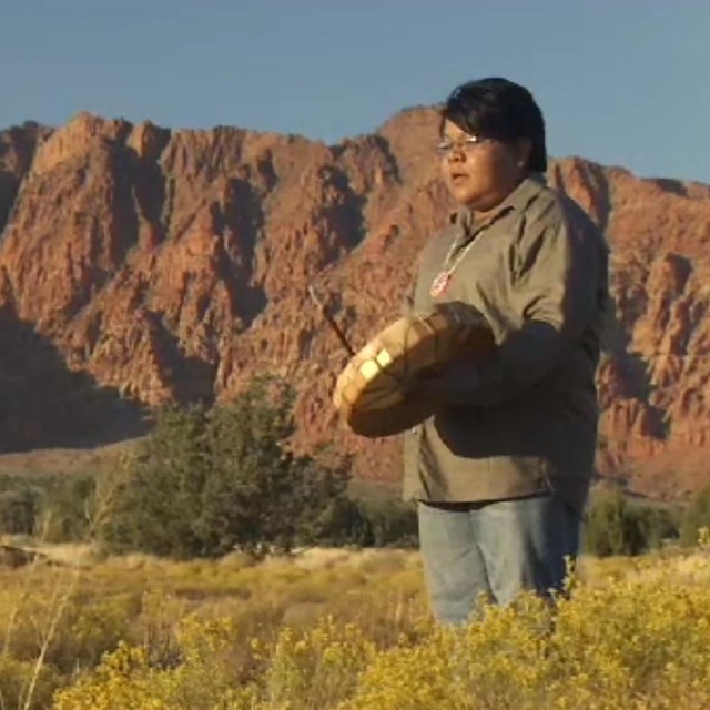 Man stands with drum in mountainous field