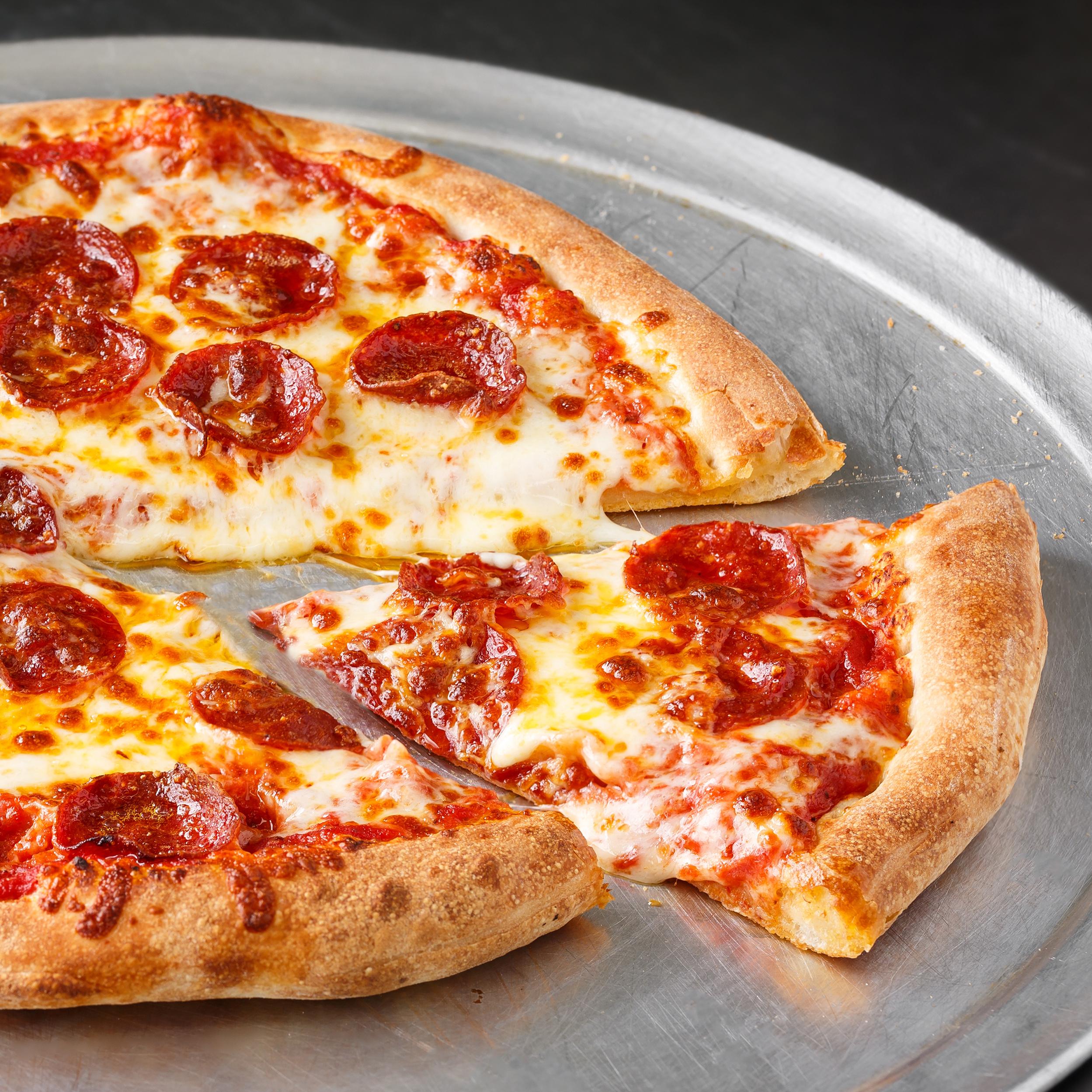 A pepperoni pizza with one slice cut out on a silver serving tray. 