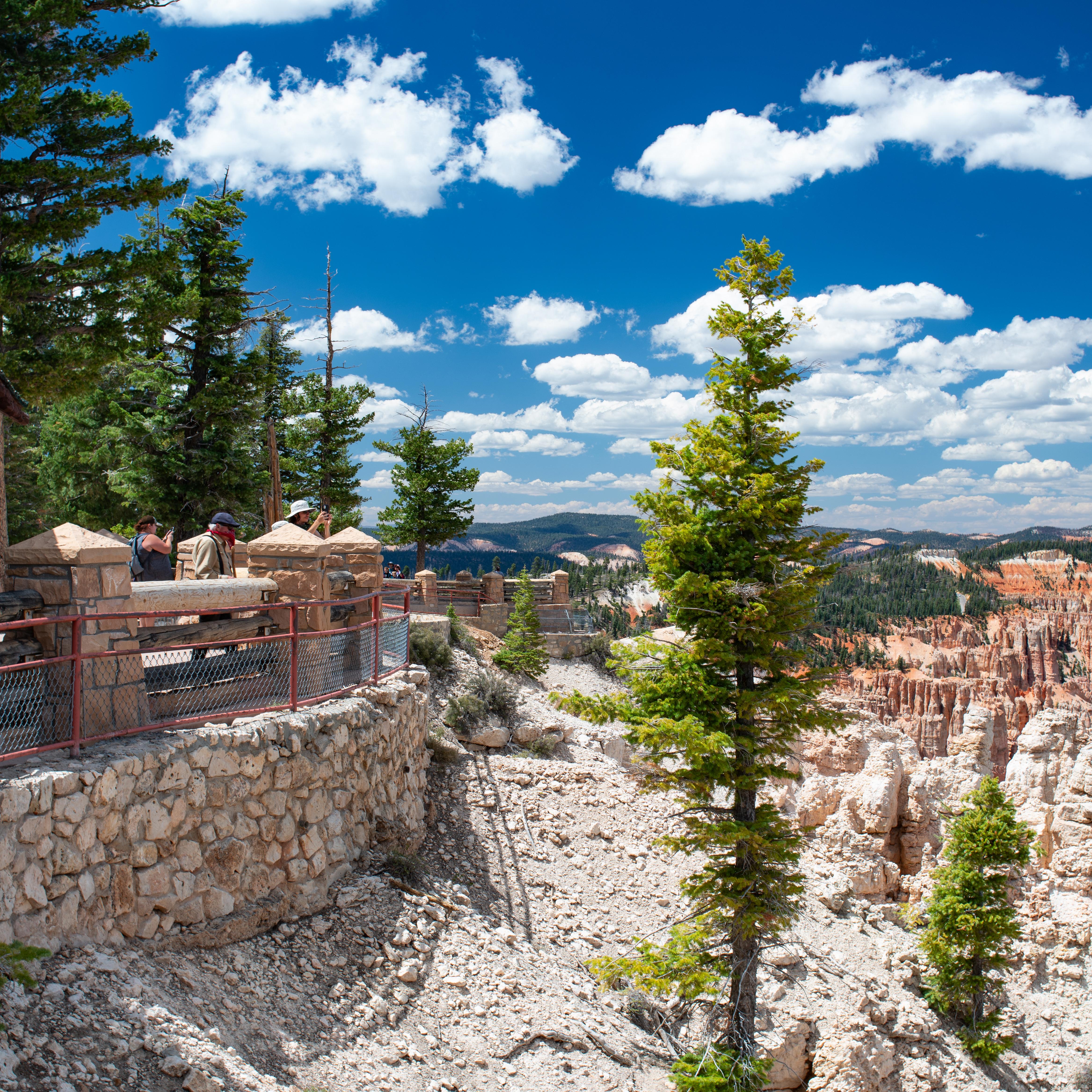 Visitors stand near a shelter with a green roof looking out at the view.