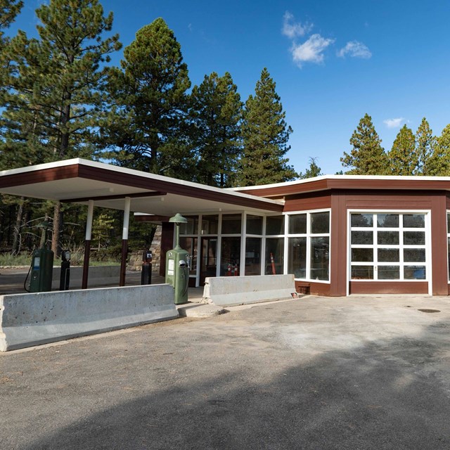 a mid-century gas station with brown painted exterior, glass windows, and flat roof lines.