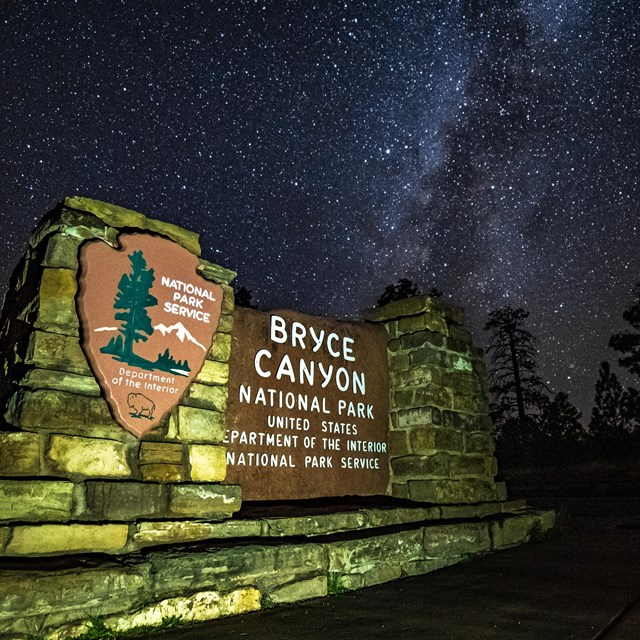 An illuminated Bryce Canyon sign with a dark sky background with lots of stars.