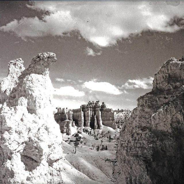 a black and white photo of a landscape of rock spires, rock walls, and slopes
