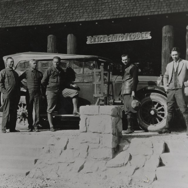 Men standing in front of a car on the steps of the Bryce Canyon Lodge