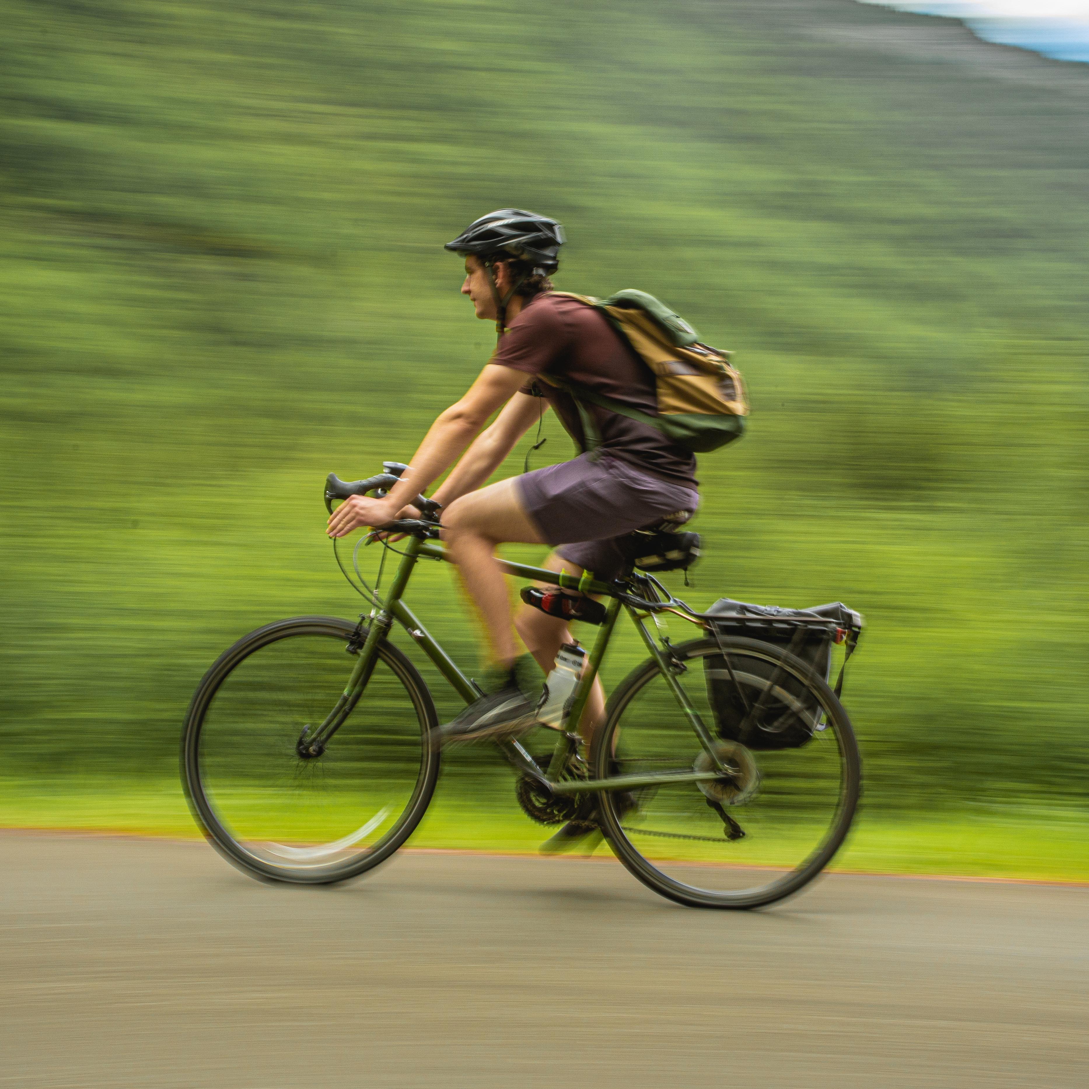 a man wearing a helmet bicycles on a path