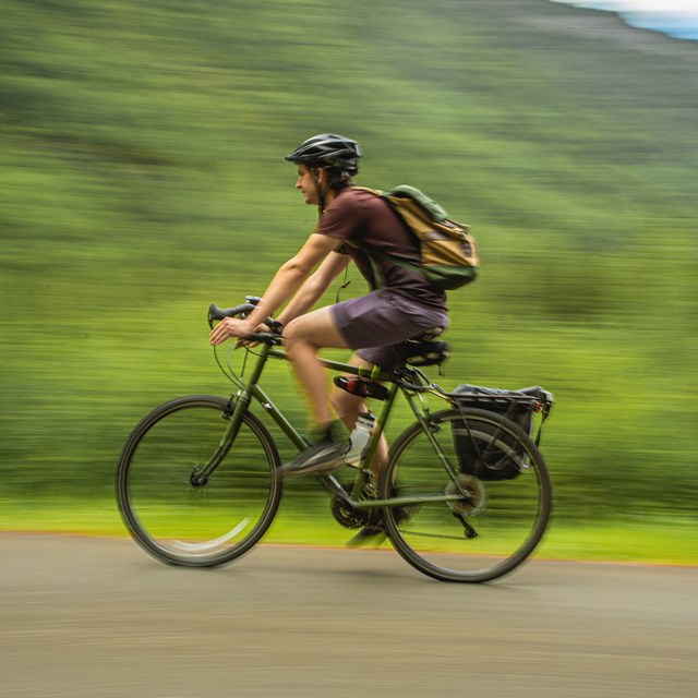 a man wearing a helmet bicycles on a path
