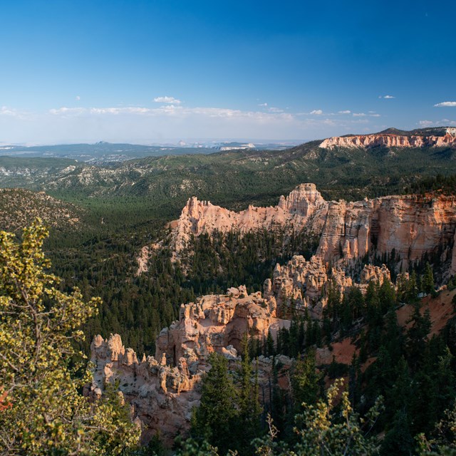 A photo showing the red rocks of Bryce in the foreground and far views in the background.