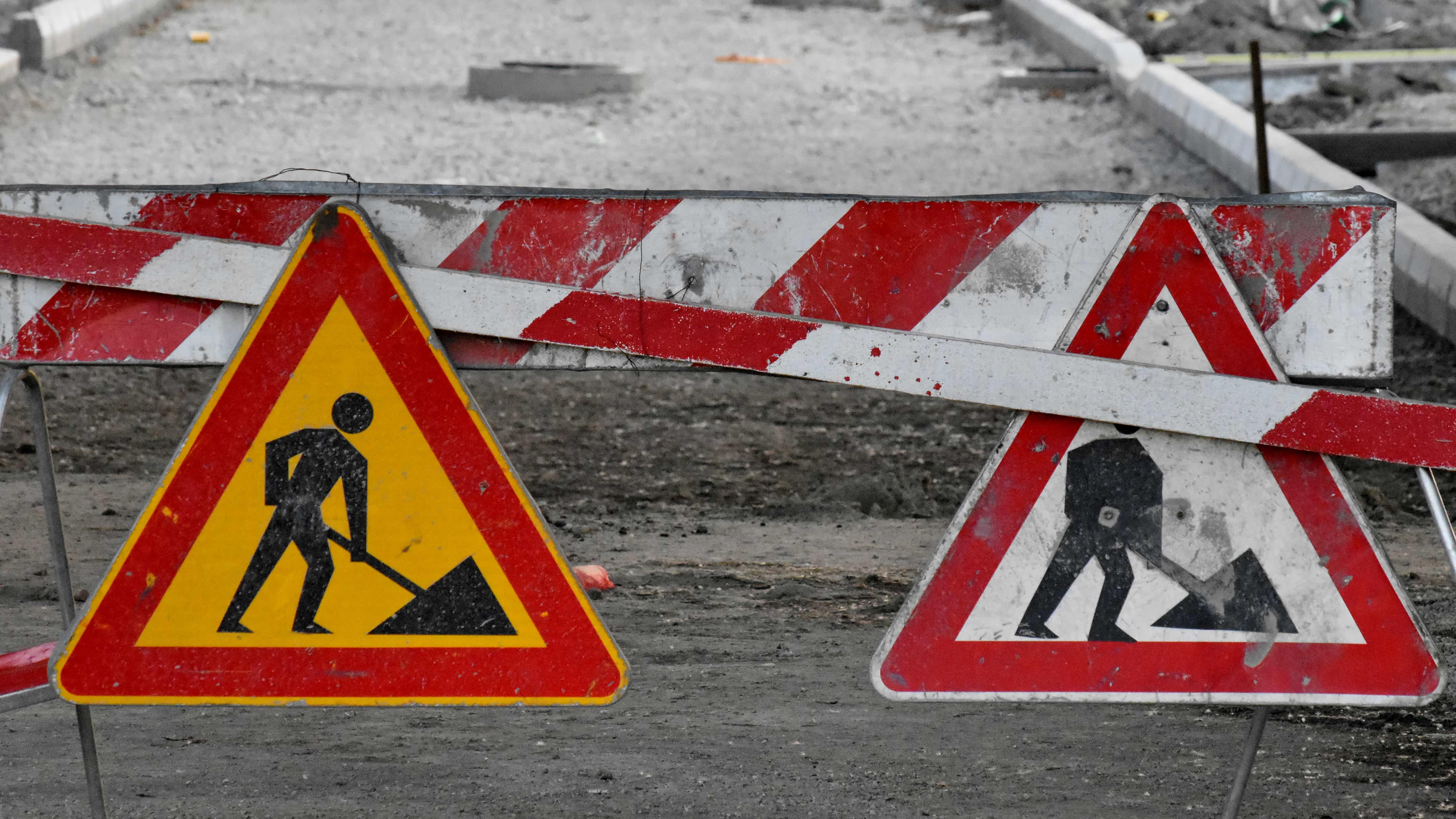 Red, yellow and white construction sign. Street in background.