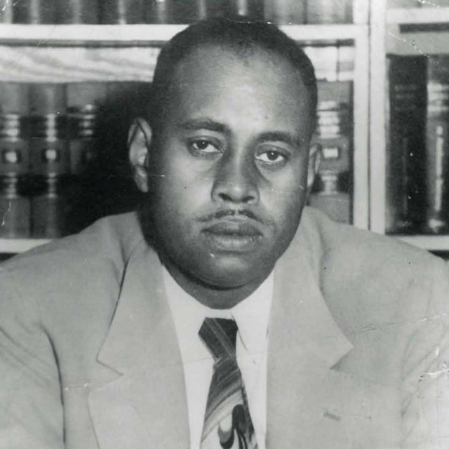 Charles Scott sits in front of a bookshelf