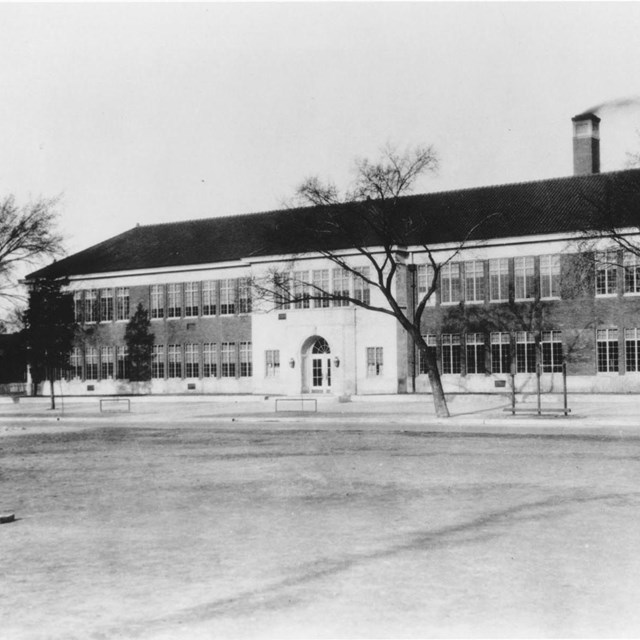 Black and white exterior of brick and cement elementary school in winter
