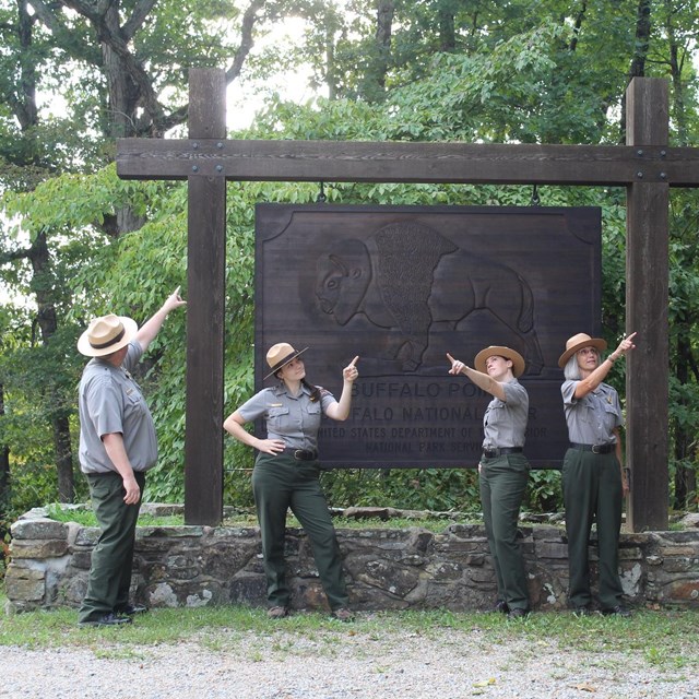 Park rangers point to unseen objects the distance.
