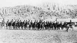Several army soldiers on horses pose for a photo