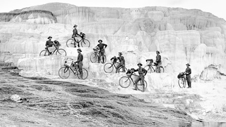 Soldiers standing next to their bikes on a natural feature in Yellowstone
