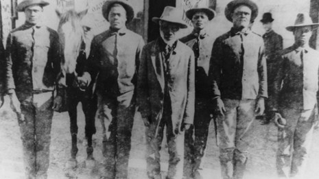 Multiple men wearing hats standing in a line