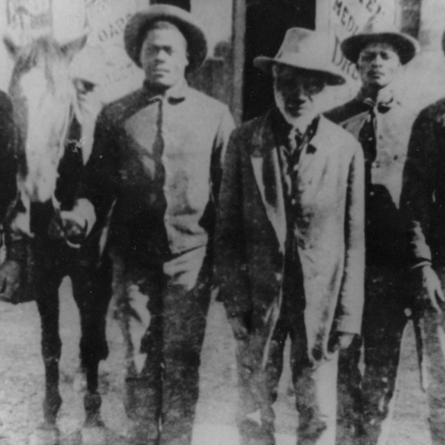Multiple men wearing hats standing in a line