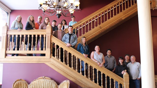 A group of people stand on a wooden staircase.