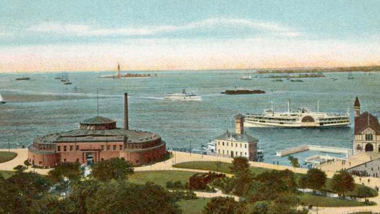 A brick building sitting by the water in a green park