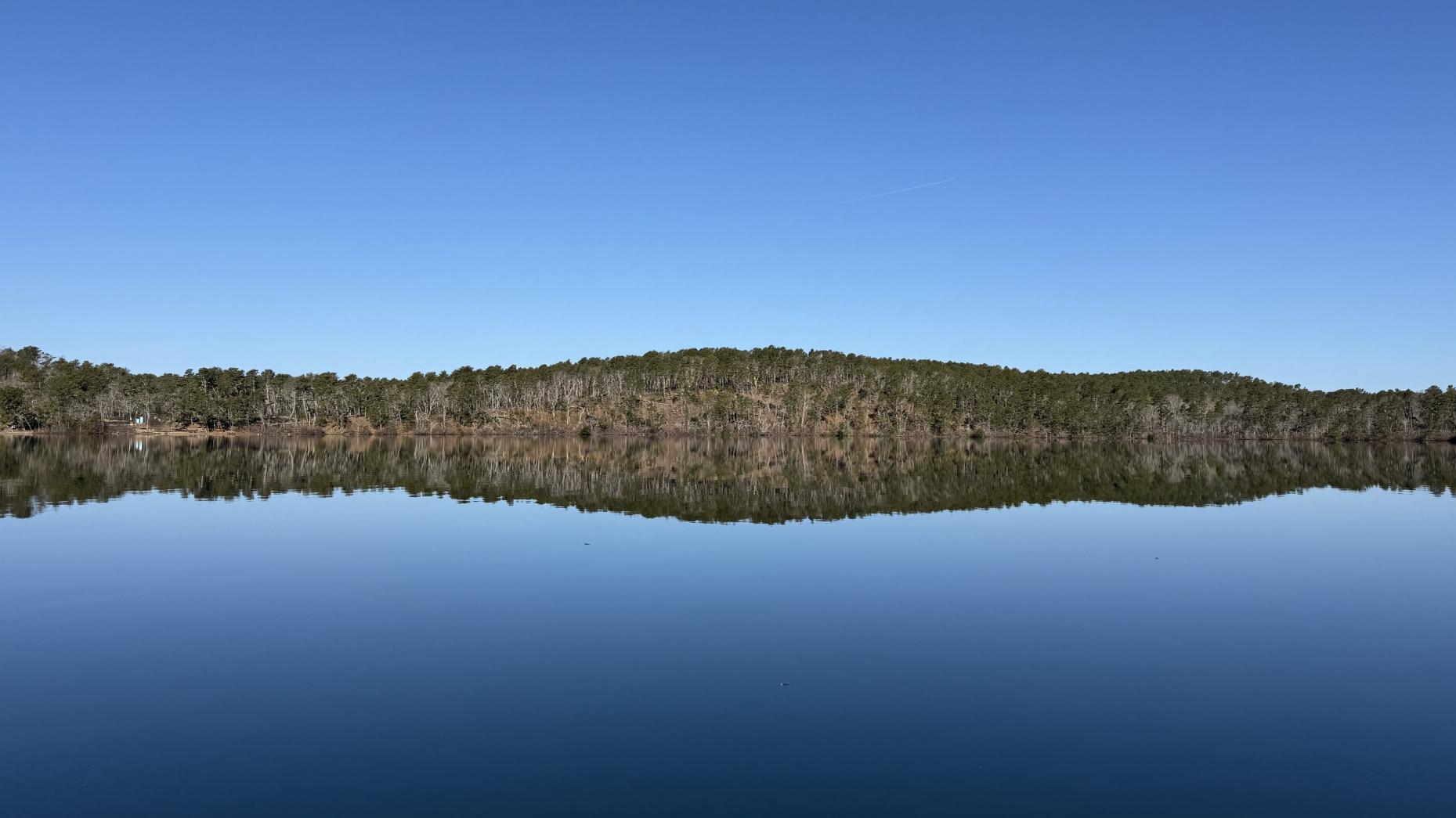 Gull Pond in Wellfleet on a very calm day. A blue sky and trees perfectly reflected in the water. 