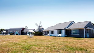 A long motor lodge sits on a grassy hill, the center of the lodge is accented by a small windmill.