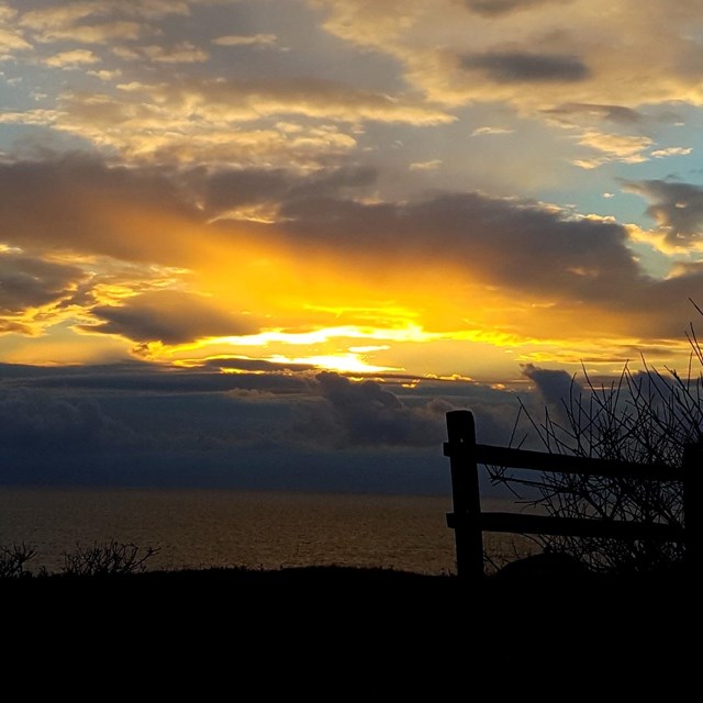 A brilliant sunrise from a vista looking down on a beach.