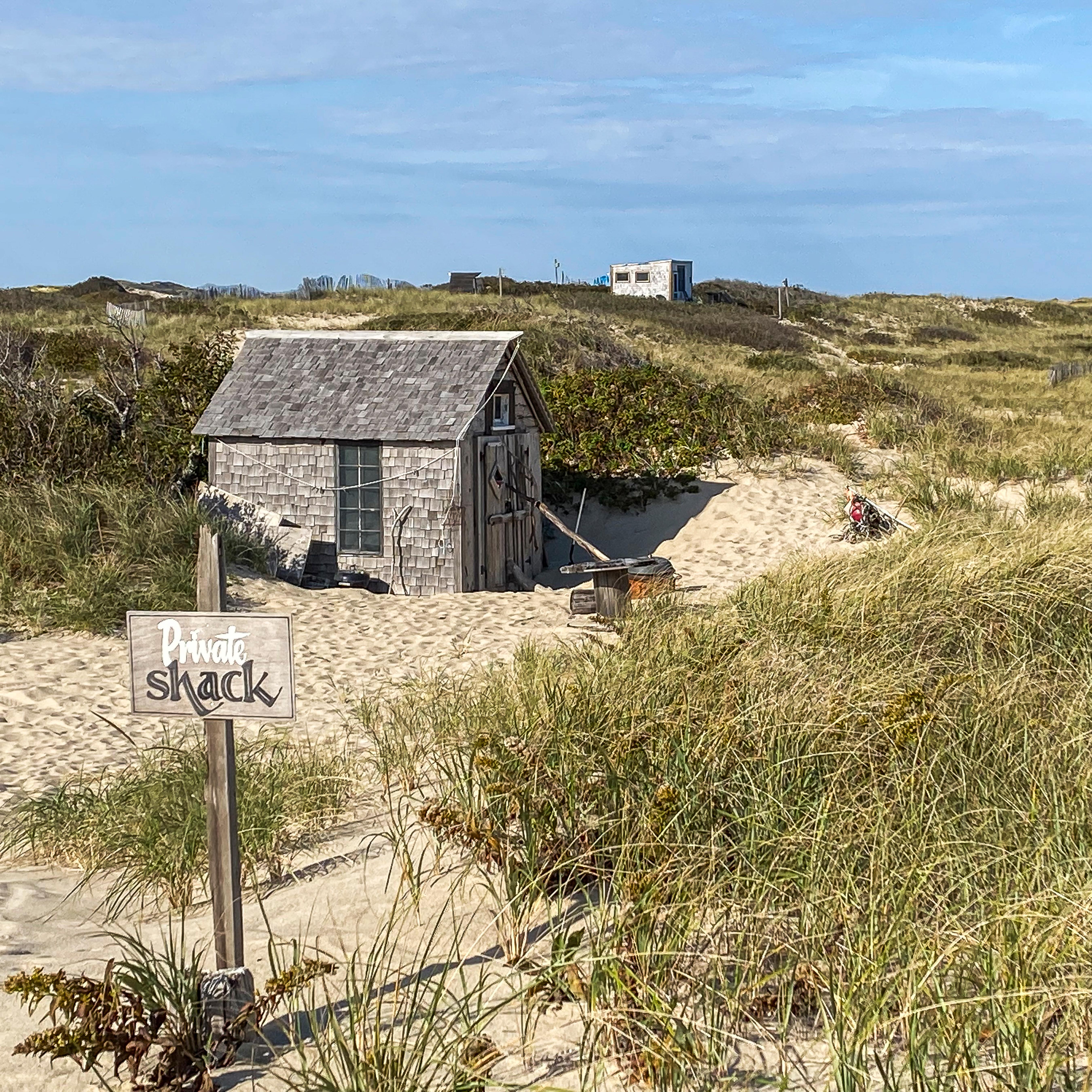 A small wooden shack nestled amongst sandy dunes.