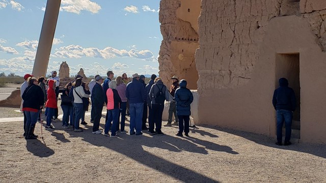 A volunteer talking to a group at a large adobe structure