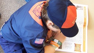 Cub scout in uniform writing in a workbook