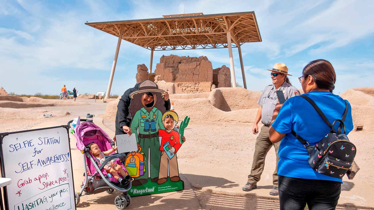A family poses for a pictures in front of the Great House while a smiling Park Ranger watches. 