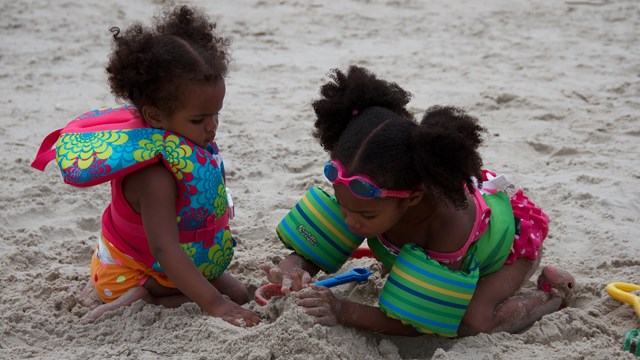 Two young girls playing in the sand.