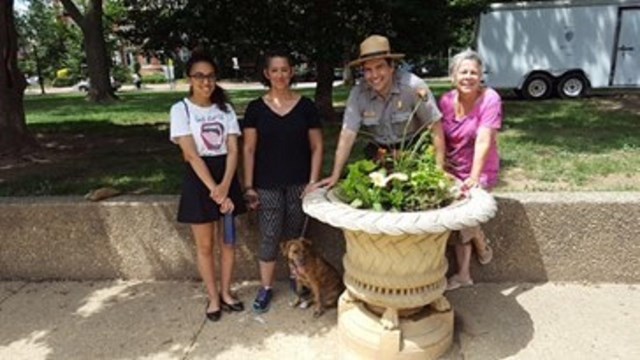 A group of people standing behind a potted urn.