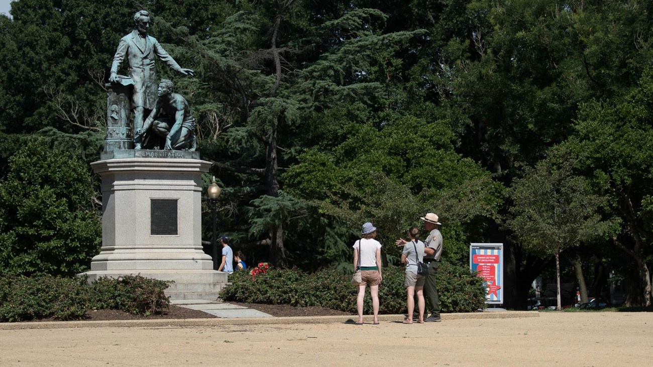 Emancipation statue with two women talking to a park ranger