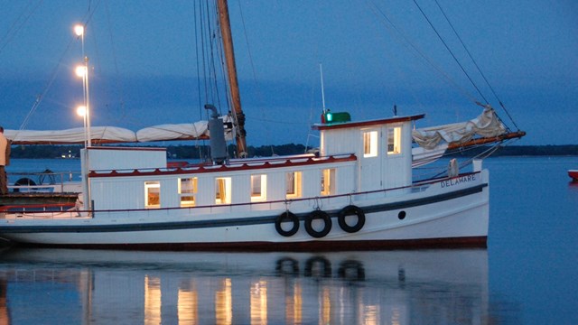 A small boat at a dock at twilight named "Delaware"