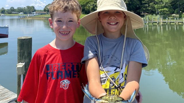 Two boys hold up a crab they caught. 