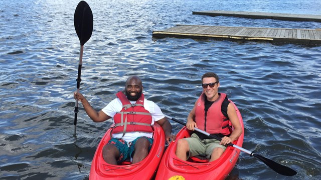 Two teachers in kayaks pose for the camera. 