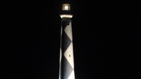 Cape Lookout Lighthouse at night with tower illuminated from below