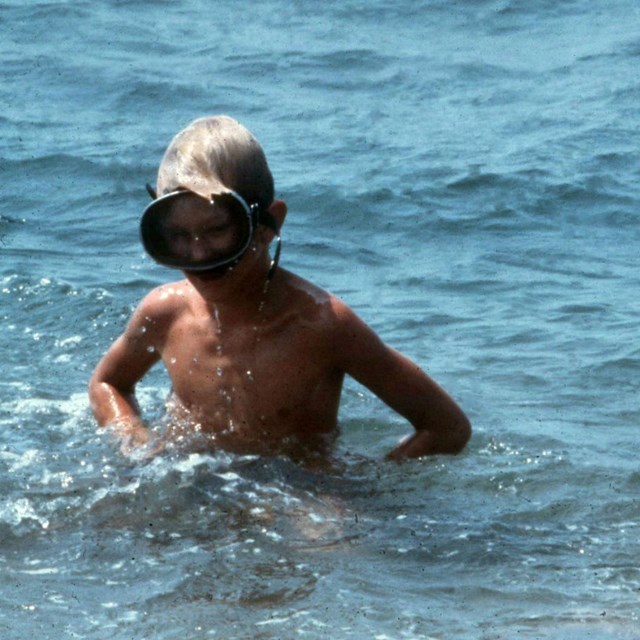 Two boys with face masks play in the water.